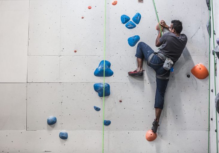 a-man-scales-the-side-of-a-rock-climbing-wall